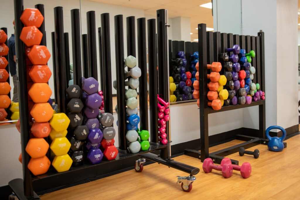 Hand weights in various colors on a rack